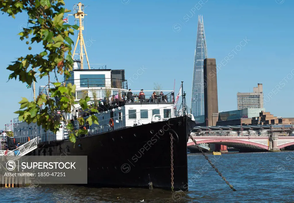 England, London, The Shard and Tate Britain with HMS President moored in the Thames near the Embankment station for more than 80 years. Built in 1918 she saw service as a convoy protection vessel in world war 1. She is now a venue for conferences etc.