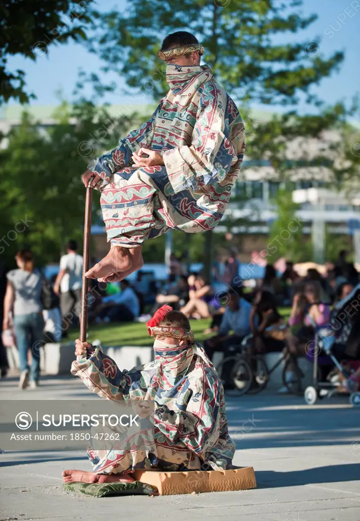 England, London, Jubilee Gardens Levitation trick being performed by street artist.