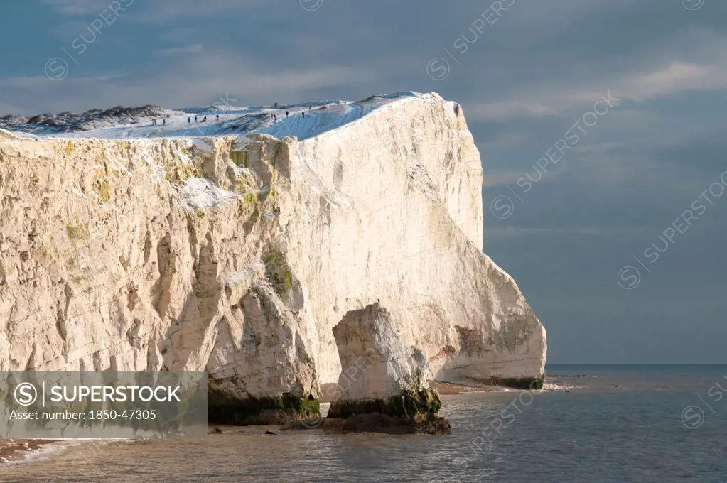 England, East Sussex, Seaford Head, Snow on cliffs with people toboganing.