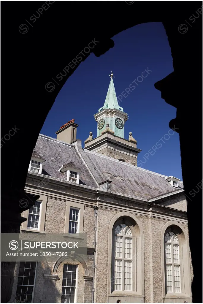 Ireland, County Dublin, Dublin City, Kilmainham Royal Hospital clock tower viewed through an arch of the courtyard cloister.