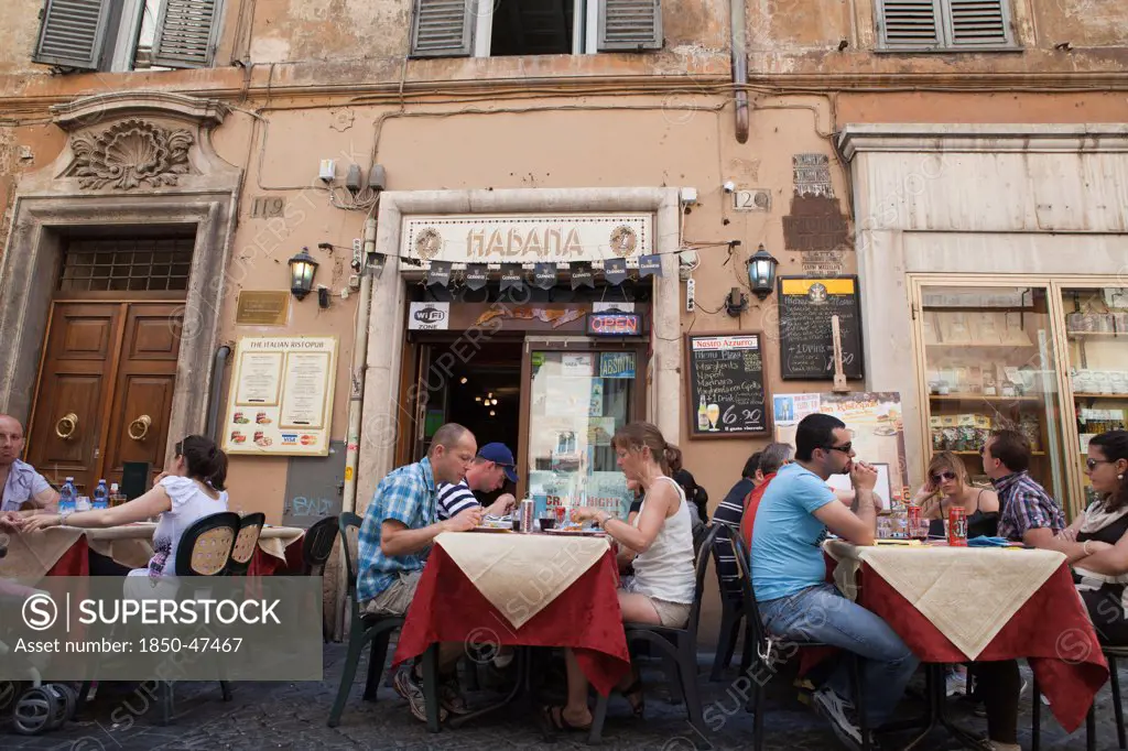 Italy, Lazio, Rome, Diners eating al fresco at a restaurant in a back street.