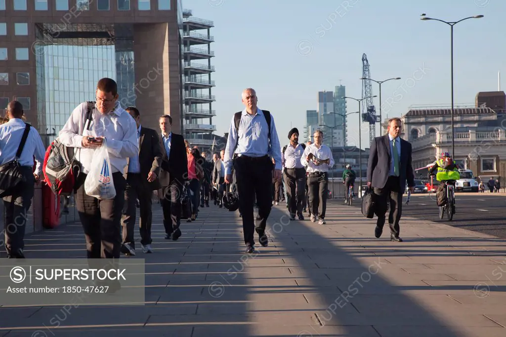 England, London, Early morning commuters crossing London Bridge towards the City Financial district.