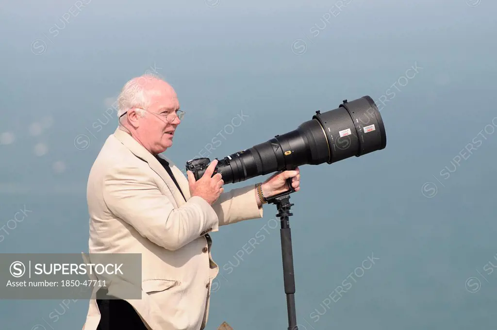 England, East Sussex, Beachy Head, Plane enthusiast photographing air display with long lens on a monopod during the Airbourne airshow.