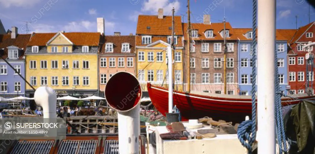 Denmark, Copenhagen, Nyhavn Canal.  View Over Boats To Pavement Cafes And Waterside Buildings.