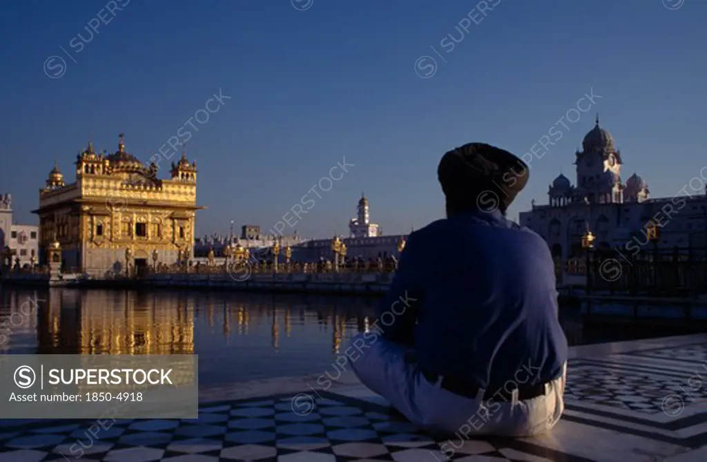 India, Punjab, Amritsar, Golden Temple With Pilgrim Sat Beside Sacred Pool In The Foreground.