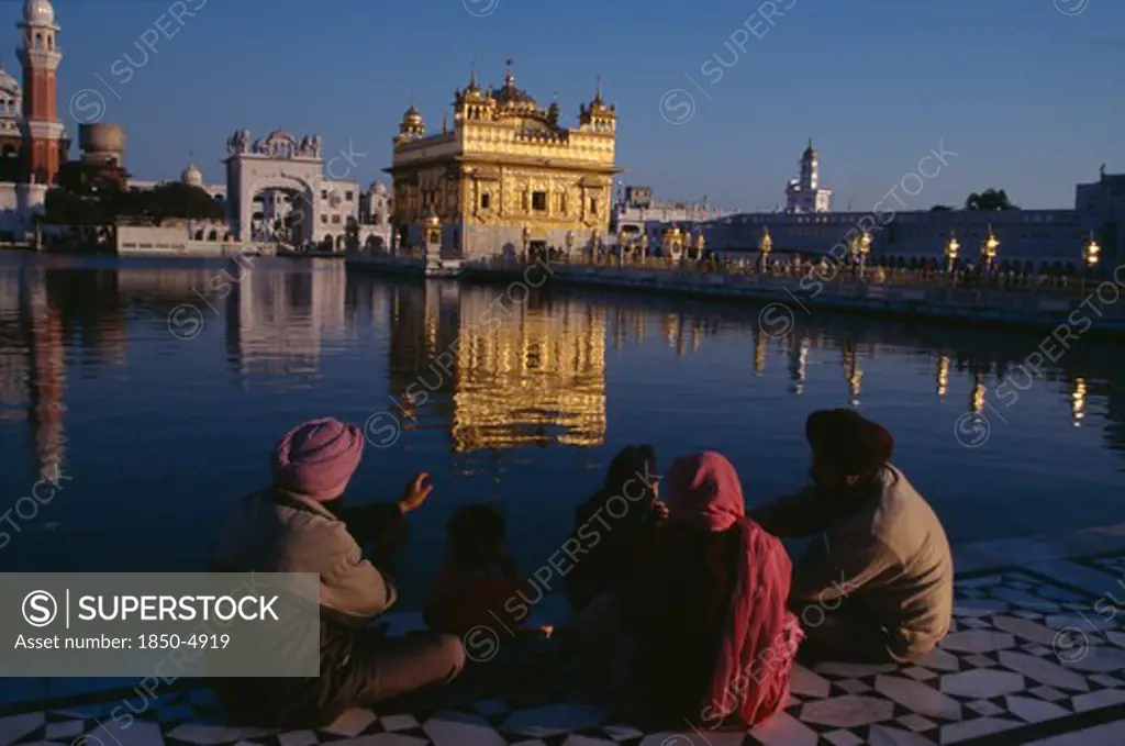 India, Punjab, Amritsar, Golden Temple.  General View With Pilgrim Group Sitting Beside Sacred Pool In The Foreground.