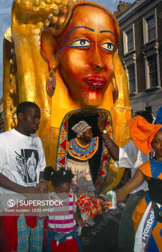England, London, Notting Hill Carnival Man and young girl in front of golden coloured float.