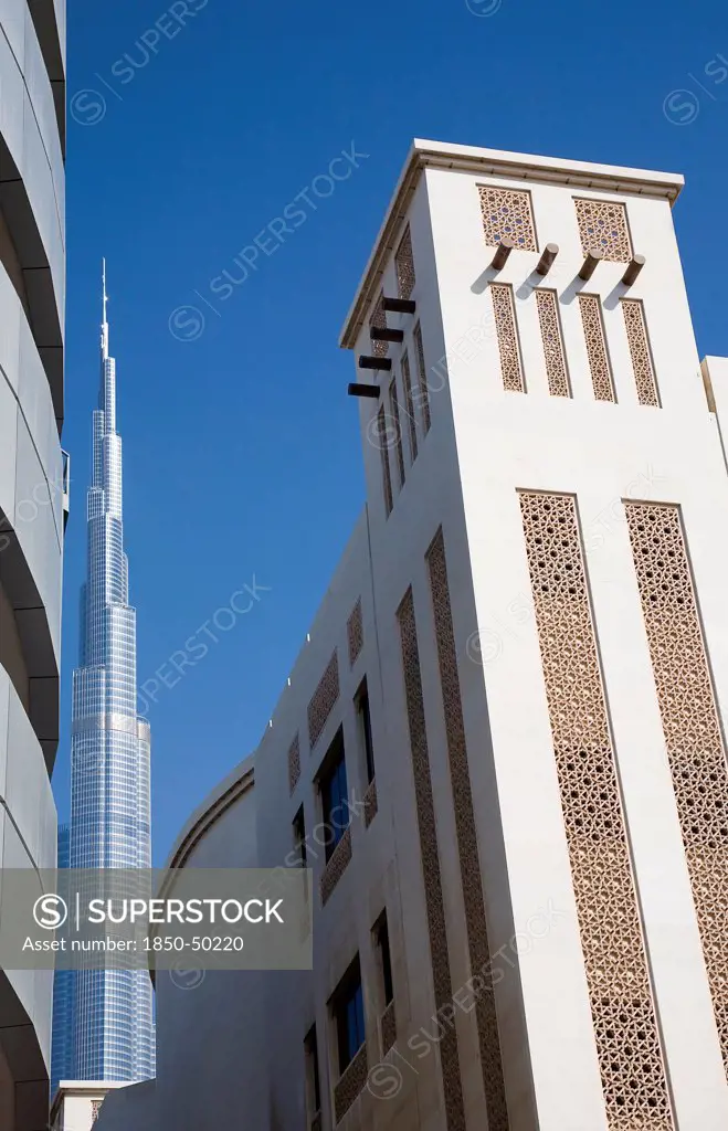 UAE, Dubai, Traditional Wind Tower design in front of Burj Khalifa tower.