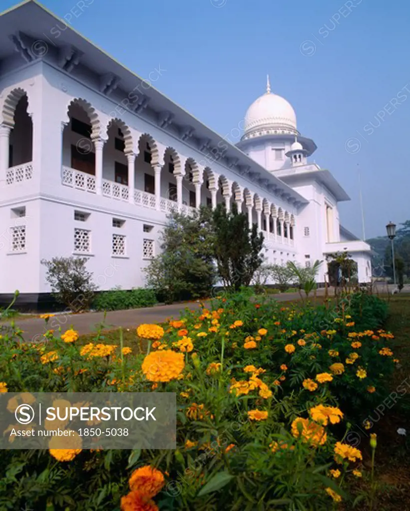 Bangladesh, Dhaka, Supreme Court Building Exterior Facade With Ornate White Arches And Orange Flowers In Foreground.