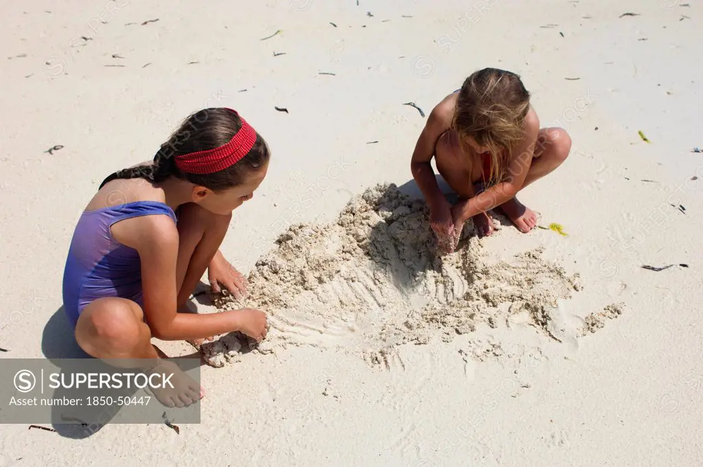Zanzibar, Paje, Two young girls playing in the hot sunshine of the sandy beach.