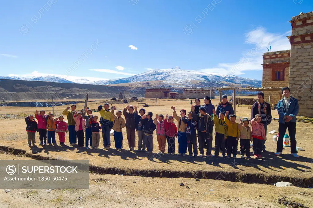 China, Szechuan Province, Tibet, School children waving outside their school.