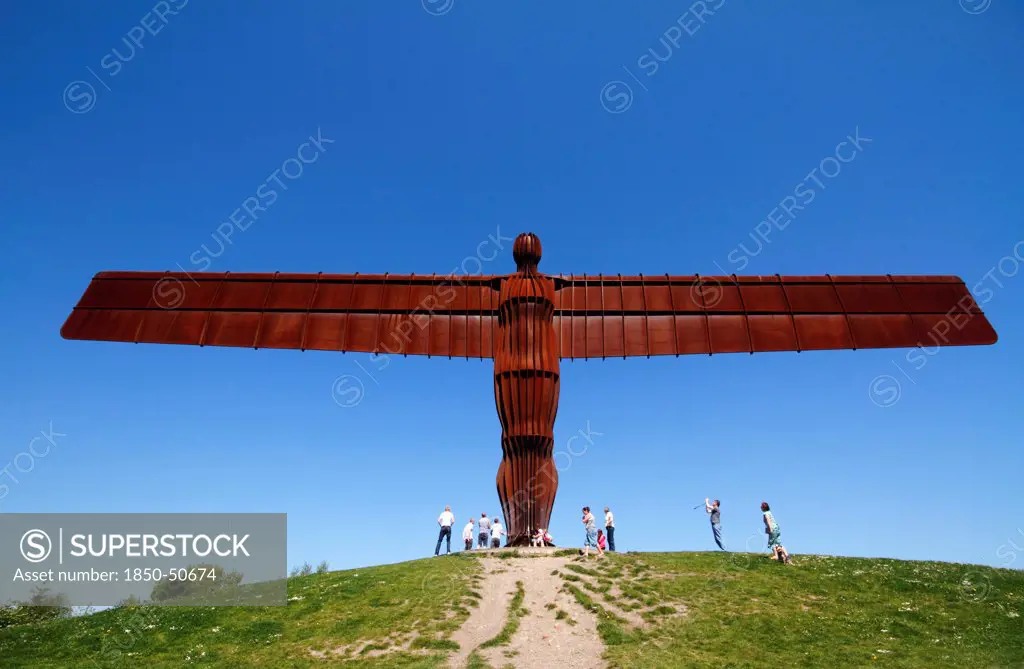 England, Tyne and Wear, Gateshead, Angel Of The North Against Deep Blue Sky Steel Sculpture By Antony Gormley Standing 20 Metres Tall With Wingspan Of 54 Metres Constructed From Steel Showing Tourists For Scale Against A Deep Blue Sky.