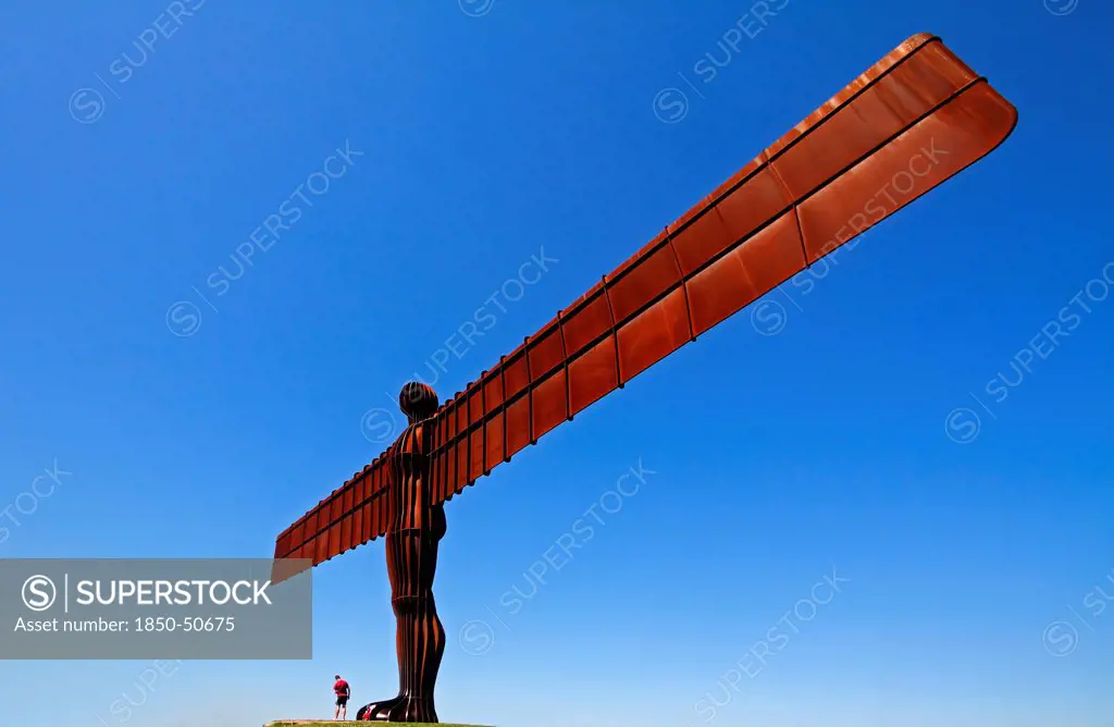 England, Tyne and Wear, Gateshead, Angel Of The North Steel Sculpture Standing 20 Metres High Designed By Antony Gormley Man Standing At Base With Child.