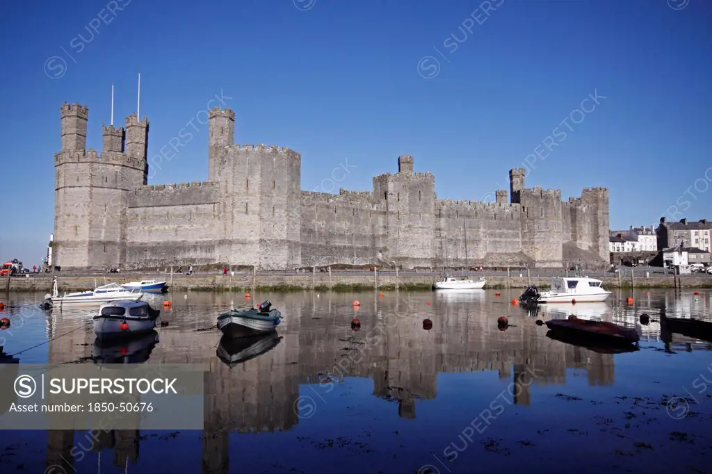 Wales, Gwynedd, Caernarfon, Caernarfon Castle Against Deep Blue Sky Overlooking The River Seiont as the tide comes in Construction Started In 1283 And Prince Charles Held His Investiture At The Castle In 1969. A UNESCO World