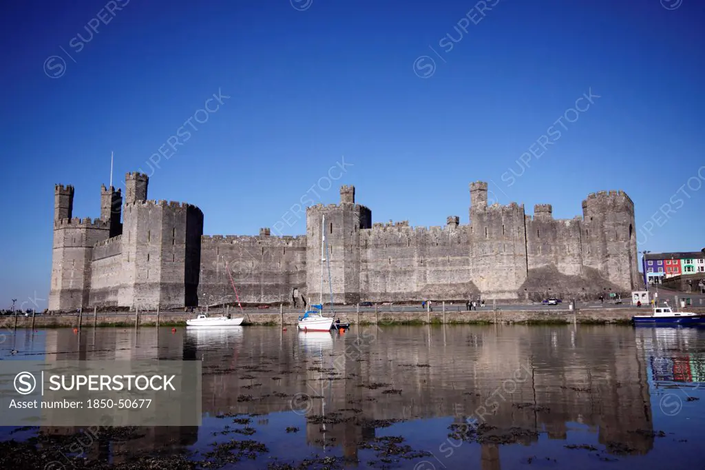 Wales, Gwynedd, Caernarfon, Caernarfon Castle Against Deep Blue Sky Overlooking The River Seiont as the tide comes in Construction Started In 1283 And Prince Charles Held His Investiture At The Castle In 1969. A UNESCO World Heritage Site.