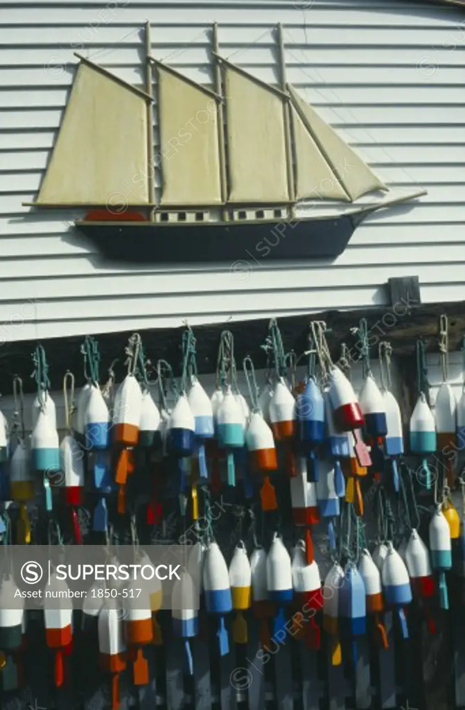 Usa, Maine , Boothbay Harbour, Lobster Buoys Hanging On Wall Of Clapperboard Building Beneath A Model Of A Three Masted Sailing Ship