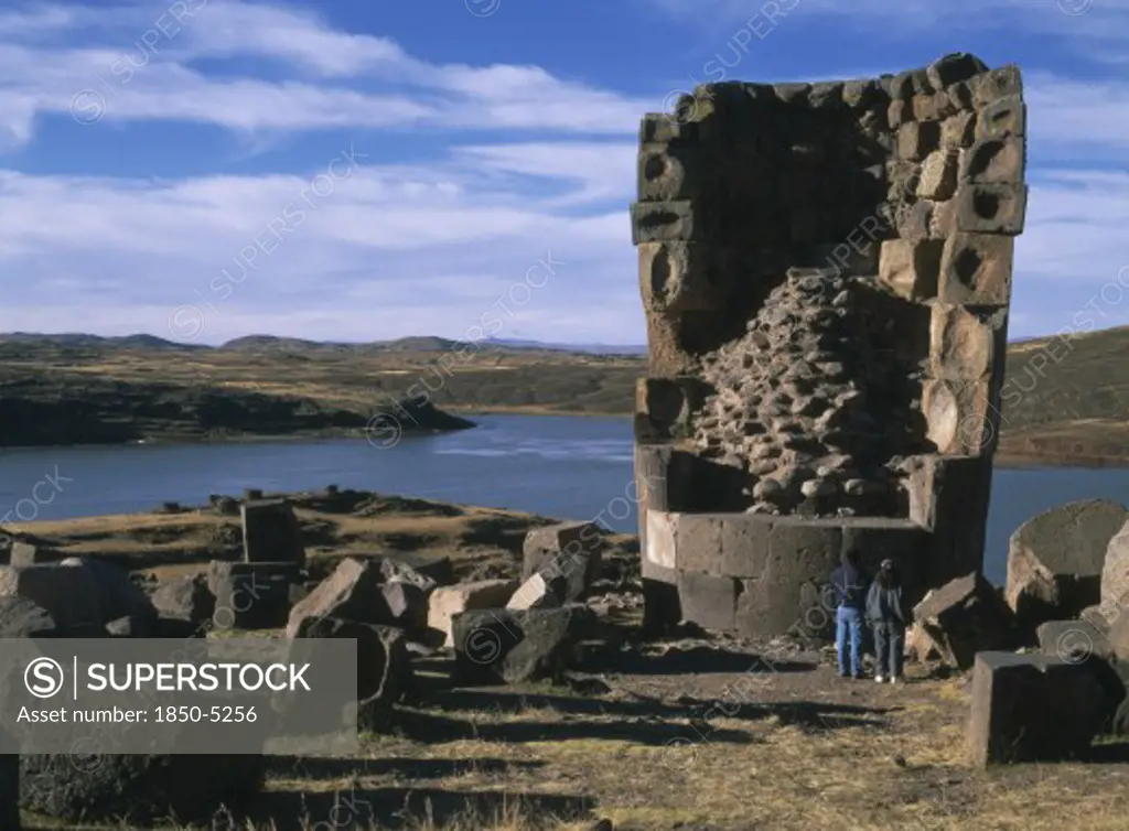 Peru, Puno Administrative Division, Puno Area, 'Sillustani.  Pre Columbian Funeral Tower, Or Chullpa, With Two People Standing At Its Base, Looking Upwards.  '