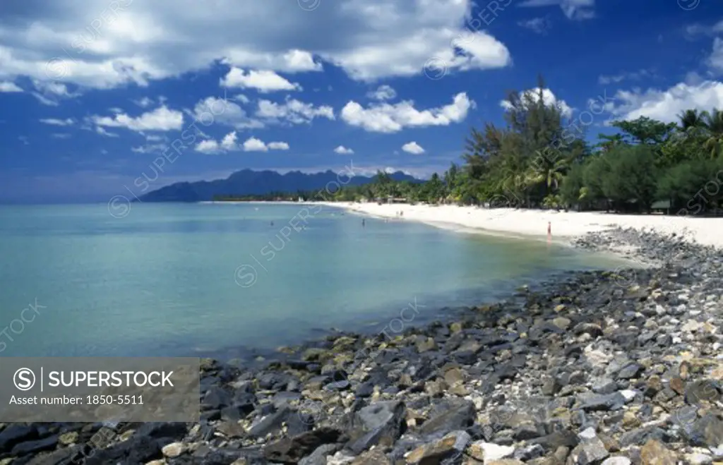 Malaysia, Langkawi, Kedah, Pantai Cenang Beach Looking Towards Gunung Mat Cincang With A Stoney Beach In The Foreground