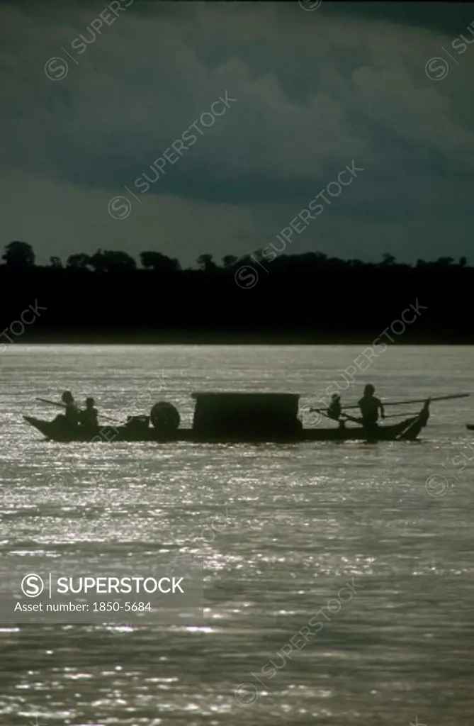 Cambodia, Stung Treng, 'Narrow Barge On The Mekong River, Oarsmen Silhouetted Against Sparkling Water.'