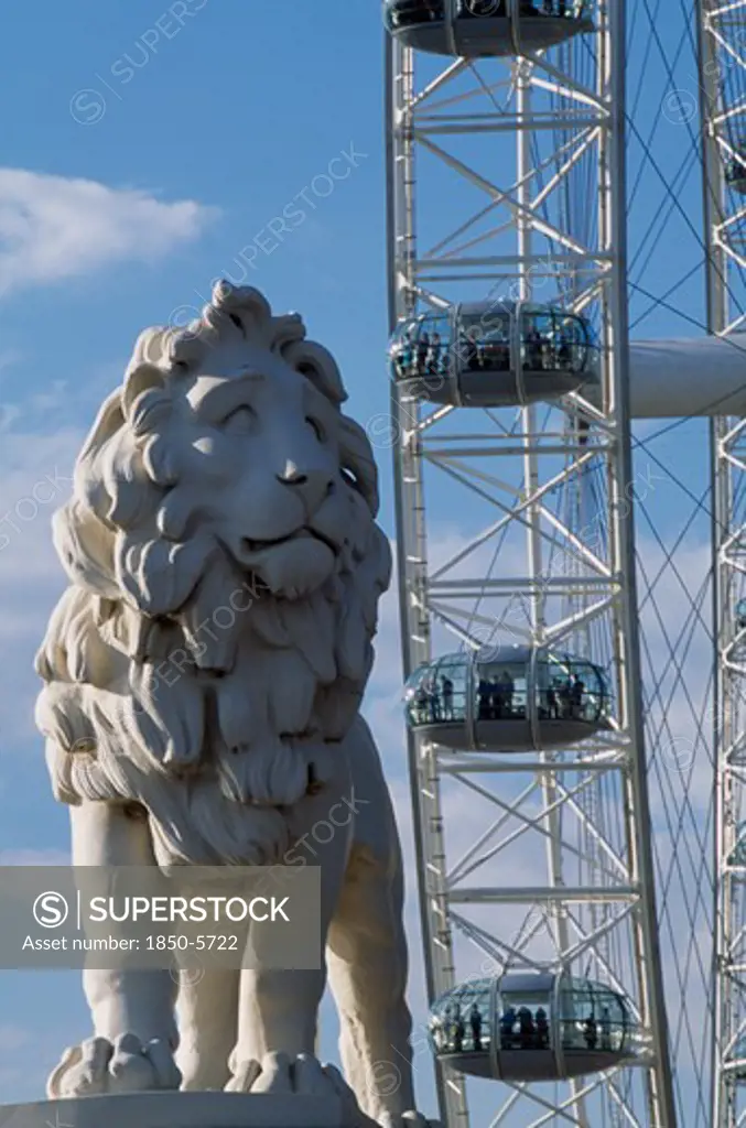 England, London, 'The London Eye, Part View Of The Wheel Rim With Capsules And Passengers Behind Statue Of Standing Lion In The Foreground  '