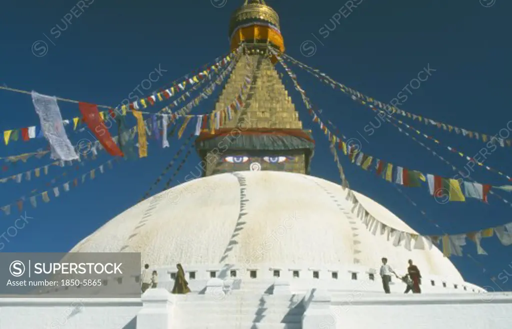 Nepal, Kathmandu, Bodhnath Stupa, Detail Of White Dome With Visitors Circling It Clockwise And Gilded Spire Hung With Prayer Flags And Painted Eyes At Its Base.