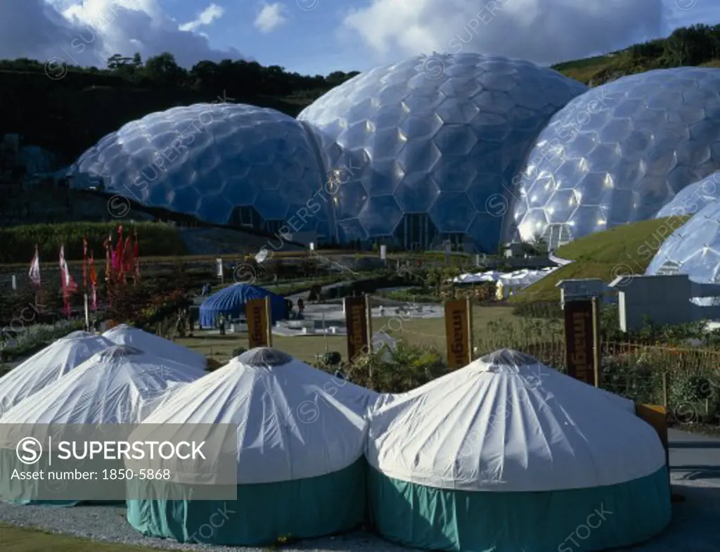 England, Cornwall, St. Austell, Eden Project.  General View Over The Humid Tropics Biome Exterior With Green And White Yurts In The Foreground.
