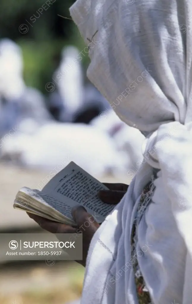 Ethiopia, Addis Ababa, 'Woman In White Head Covering Reading From Book During Ceremony At St George Church, Kidus Giorgis.'