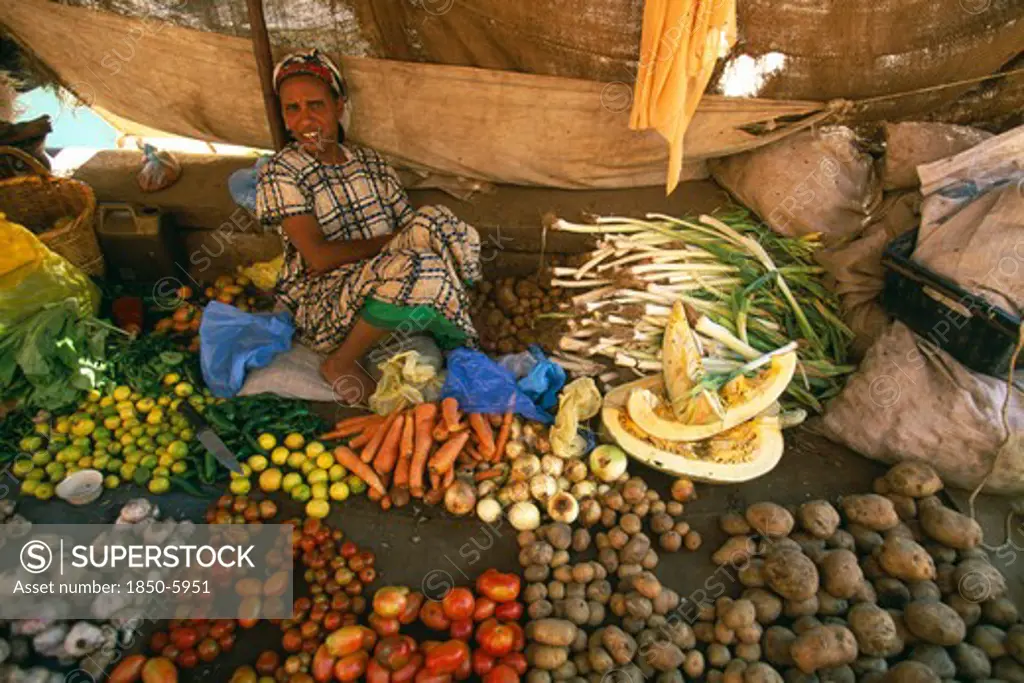 Ethiopia, Harerge Province, Harer, Market Outside The City Walls.  Female Vendor Sitting Behind Display Of Vegetables Laid Out On The Ground In Front Of Her.