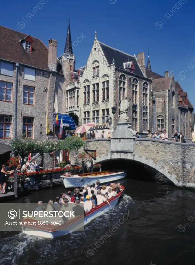 Belgium, West Flanders, Bruges, Tourists On Canal Boat Trips Below A Bridge And Old Buildings