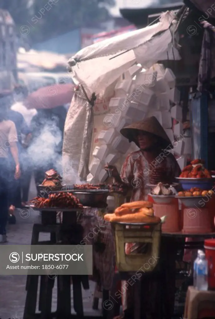 Vietnam, Mekong Delta, Vinh Long, Woman Cooking Various Meat Dishes At A Roadside Market Stall.