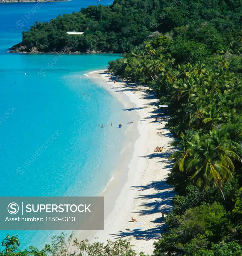 West Indies, Us Virgin Islands, St Johns, 'Trunk Bay. View Over Tree Covered Coastline With Bright Blue Water And Narrow, Curved, Sandy Beach With Distant Sunbathers And Swimmers.  '