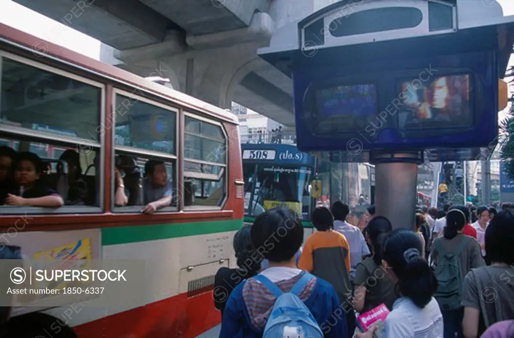 Thailand, Bangkok, Bus And Passengers At Bus Stop In Siam Square Beside One Video Screen Showing Bus Times And Another A Music Video