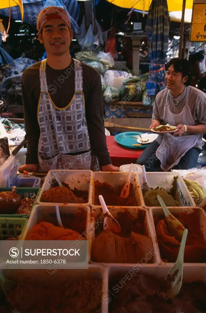 Thailand, North, Chiang Mai, Wholesale Food Market.  Male Vendor Behind Stall Selling  Selection Of Curry Pastes Displayed In Plastic Bowls.