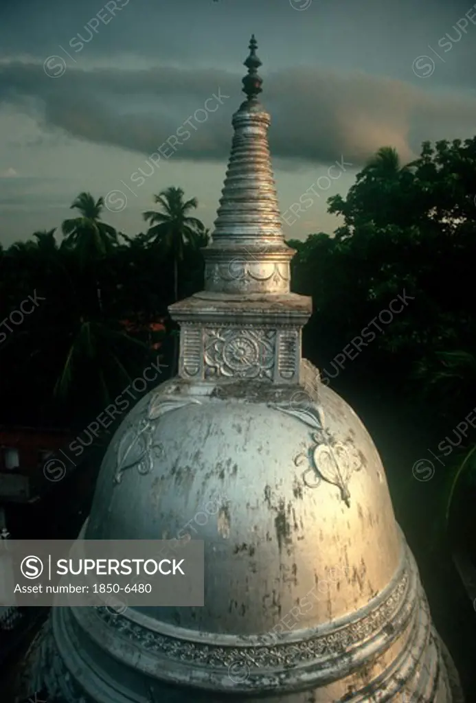 Sri Lanka, Anuradhapura, 'Carved Dagoba Near Isurumuniya Rock Temple, Damaged Surface Shining Silver / White In Low Light, Surrounded By Trees.'