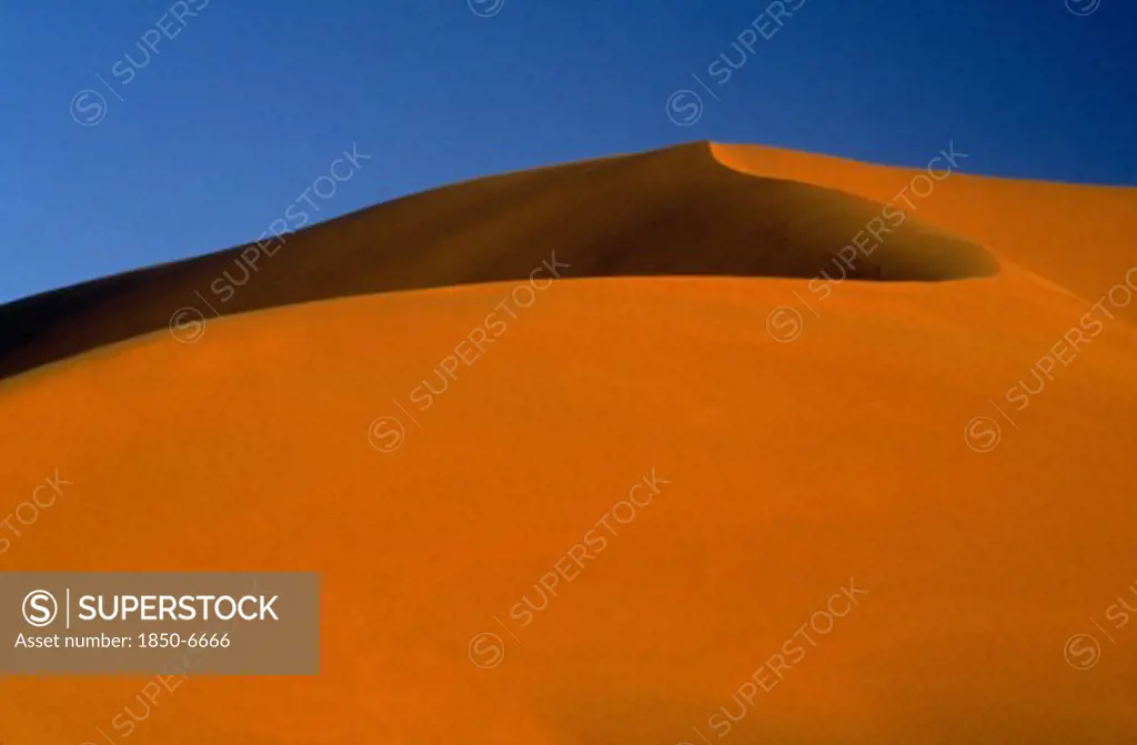Libya, South West, Achan, Large Orange Desert Sand Dune With A Clear Blue Sky