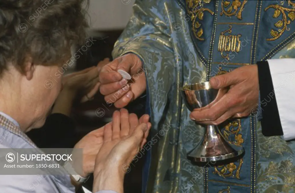 England, Religion, Anglican, Woman Holding Out Cupped Hands To Receive The Host From Priest During Anglican Service.  Cropped View.