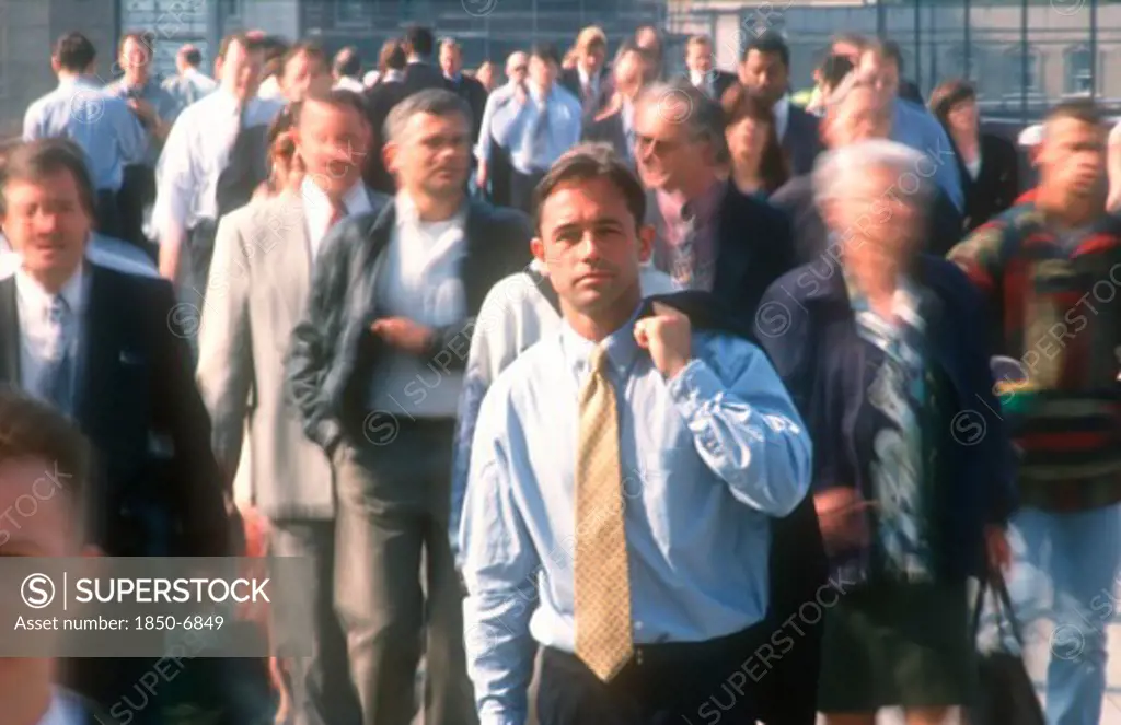 Business, Commuters, City Businessman In Shirt And Tie Holding Suit Jacket Over His Shoulder Standing Motionless Surrounded By Crowds In Blurred Movement.