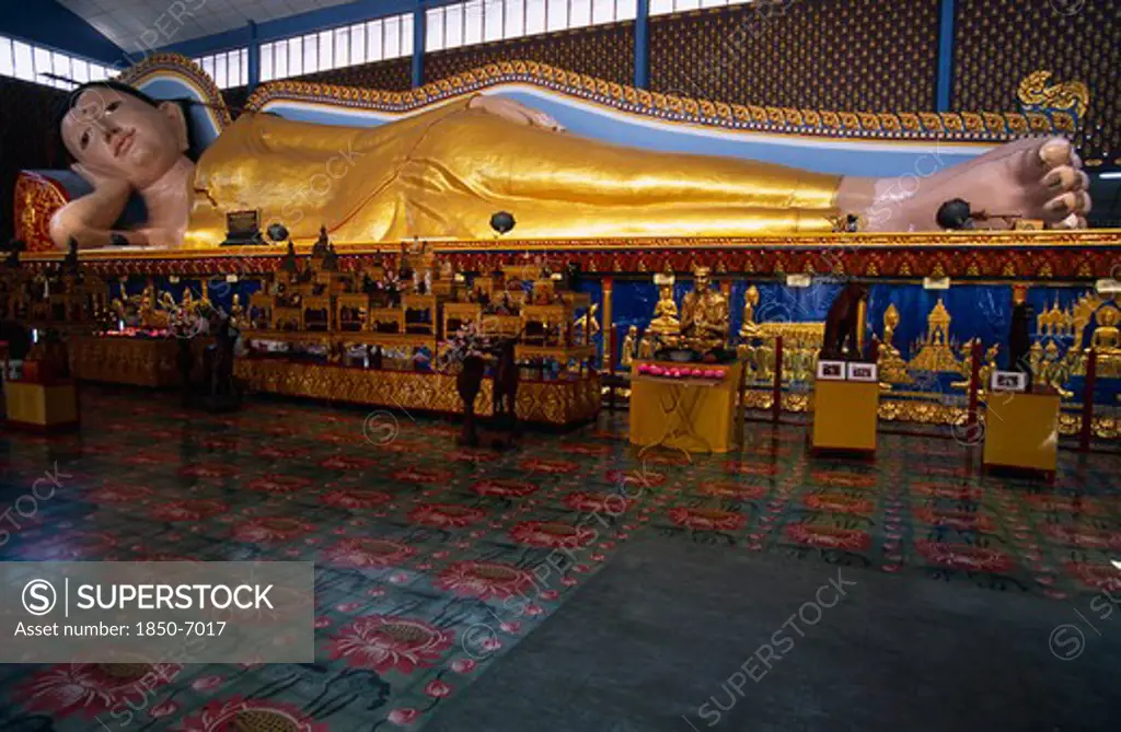 Malaysia, Penang, Georgetown, Wat Chayamangkalaram.  Interior With 32 Metre Long Reclining Buddha Lying Behind Display Of Various Smaller Figures And Statues.