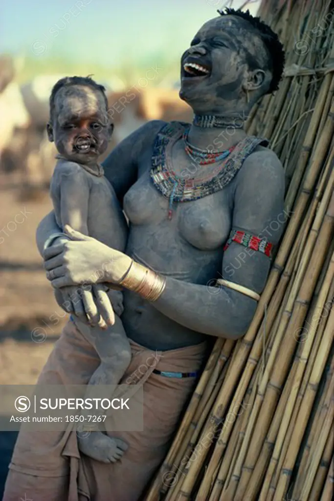 Sudan, Mundari, 'Agar Dinka Woman Decorated With Dust, Holding Young Son In Her Arms And Laughing. Woman Wearing Marriage Beads Around Her Neck And White Ivory Bracelet On Her Arm.'