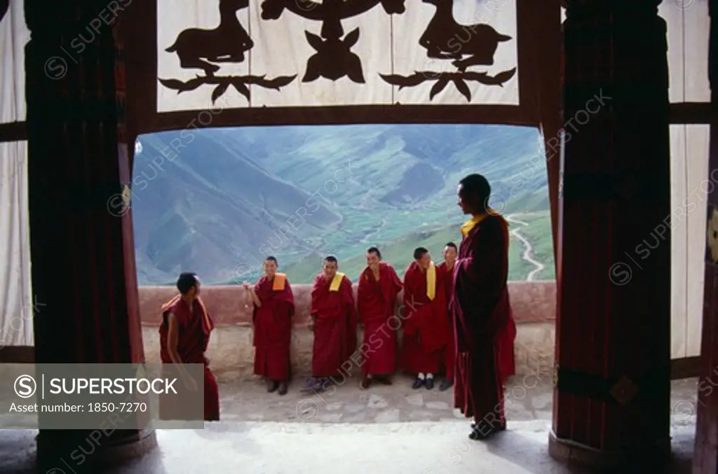 China, Tibet, Gandeh Monastery, Monks On The Balcony Overlooking The Valley Below