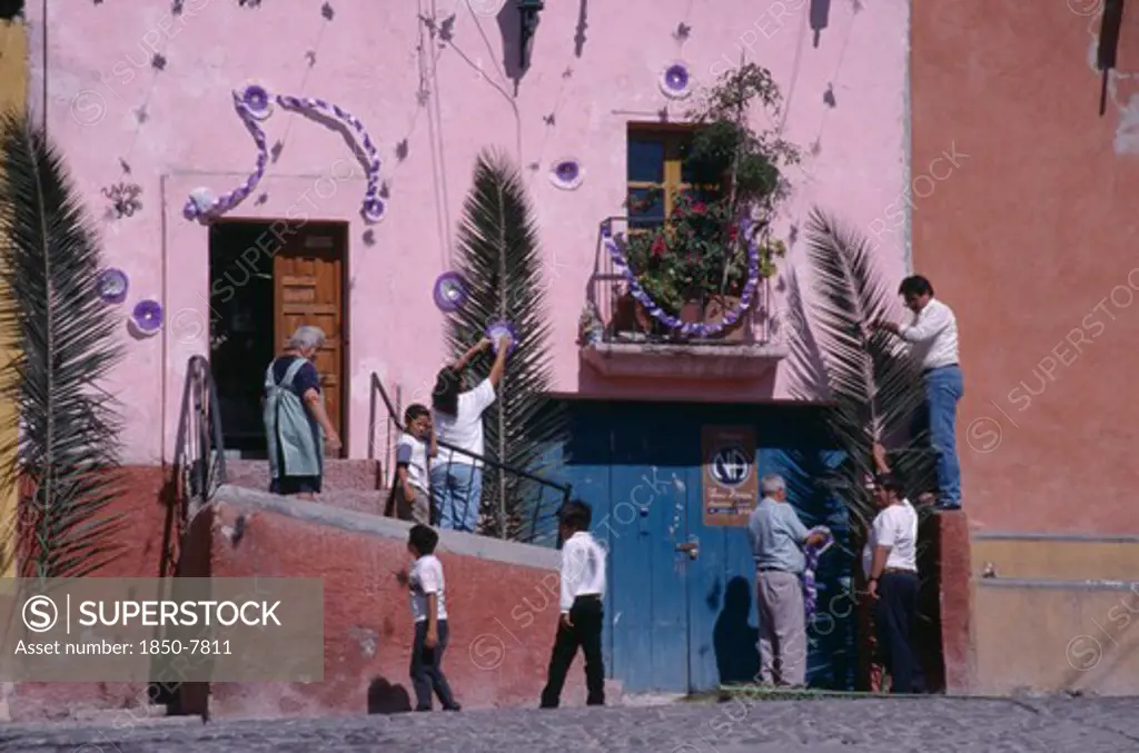Mexico, Guanajuato, San Miguel De Allende, People Decorating Exterior Of House With Palm Fronds And Streamers For Palm Sunday Celebrations.