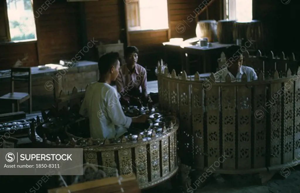 Myanmar, Mandalay, Musicians Playing Classical Musical Instruments Comprising Of Drums And Percussion Instruments In An Elaborately Carved Circle. Pat Waing