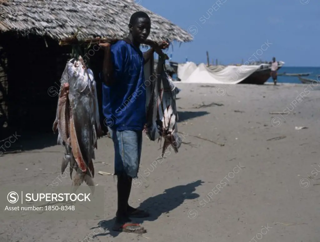 Tanzania, Pangani, Fisherman Standing On The Beach With Some Of His Days Catch