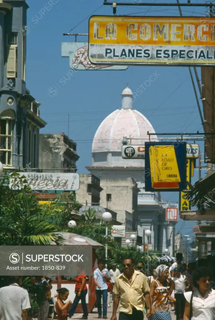 Cuba, Cienfuegos, 'Busy Street Scene With People, Hanging Shop Signs And Dome Of White Building Beyond.'