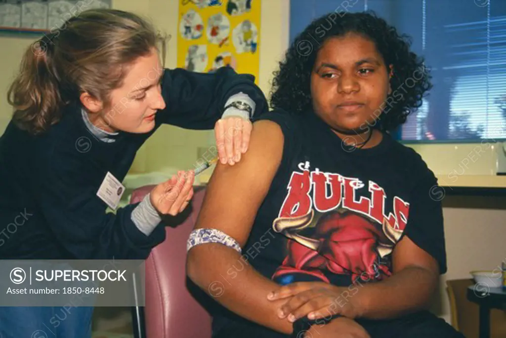 Australia, Western Australia, Kalgoorlie, Aboriginal Girl Receiving Rubella Vaccination From Female Nurse.