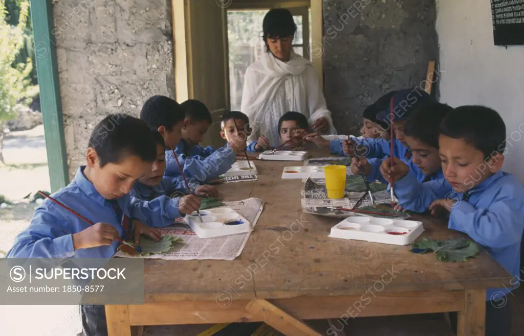 Pakistan, Northern Areas, Sherqillah, Female Teacher At Boys School With Pupils In Art Class.