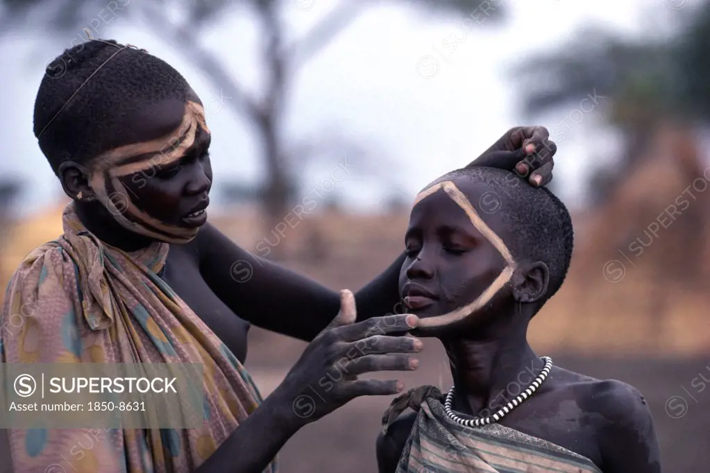 Sudan, Tribal People, Dinka Girl Decorating The Face Of A Friend Using Dung Ash Mixed With Water Or Cattle Urine.