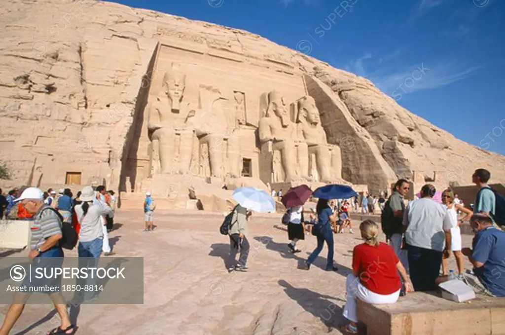 Egypt, Nile Valley, Abu Simbel, Sun Temple Of Ramses Ii.  Tourists Outside Entrance Flanked By Four Colossi Of Ramses Ii.