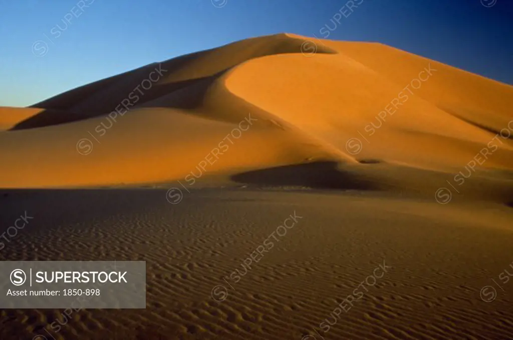Libya , South West  , Achan, Orange Desert Sand Dunes Against A Clear Blue Sky