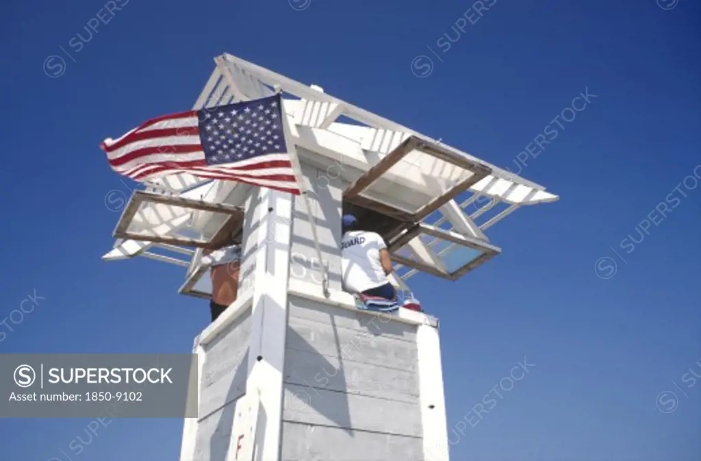 Usa, Florida, Fort Lauderdale, Life Guard Sitting On Watch Tower Flying The Stars And Stripes Flag